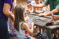 Children sitting at a wooden picnic table. They are doing the activity at Wonder Wednesday.