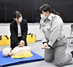 羽金さん（右）に胸骨圧迫をする際の体勢を教わる記者。焦る気持ちから、リズムが速くなってしまった