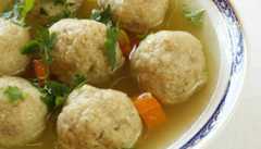 Close-up of Matzo ball soup decorated with herbs and carrots