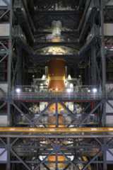 The orange core stage of the Artemis II rocket with white boosters on each side fully stacked inside the Vehicle Assembly Building at NASA's Kennedy Space Center in Florida on Saturday, Oct. 18, 2025.