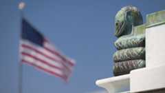 Snake statue on building with American flag in background.