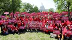 Large group of nurses outside holding banner and signs "Nurses for Democracy"
