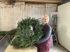 TNH-L-RHODESSISTERSSONYA-1128 Sonya Anderson-Heiden of Rhodes Sisters Christmas Tree Farm holds up one of the Huntsburg Township farm's wreaths. (Bryson Durst -- The News-Herald)