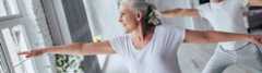 Older adult woman stretching in front of a window