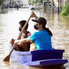 woman and child in a boat on a flooded street