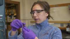 Anna Robuck in goggles and gloves working in lab