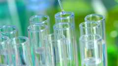 a dropper putting drops into a group of test tubes