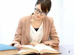 woman reading a book while sitting at a table