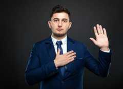 man holding hand over his chest and his other in the air to make a pledge