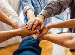 people standing in a circle with their hands in the middle