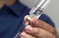 Male hands filling a syringe with the right dosage for an insulin shot.