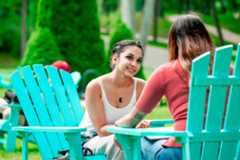 Two students talking in Adirondack chairs outside