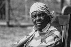 An older woman sits in a rocking chair outside