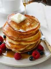 Syrup drizzling onto a stack of pancakes.