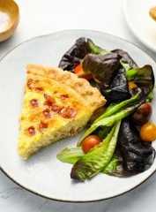 Slice of quiche Lorraine on a plate with a salad.