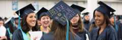Students at graduation, one of the hats says 'believe in yourself'