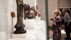 Three visitors looking at objects on display.