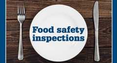 Plate, fork and knife on a wood table with the words food safety inspections on the plate.
