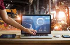 Mão tocando em um notebook aberto com representações visuais de maquinas.