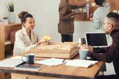 Group of people sharing pizza in an office environment