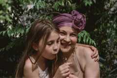 A Mummy's Wish mother, Olga holds her daughter whilst she blows a dandelion flower.