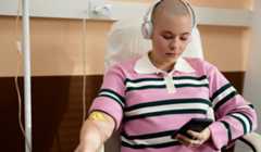 Woman in chair having cancer treatment while listening to music