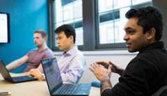 experts working together at a table with laptops open