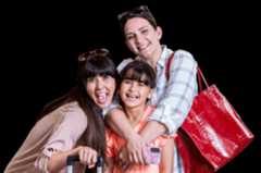 Close up photo of two women and one girl smiling with luggage.