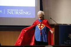 Loretta Ford, former School of Nursing dean, dressed in a Superman costume with a cape, exuding strength and confidence.