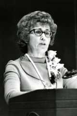 A woman in glasses, Loretta Ford, delivers a speech at a podium, showcasing her leadership as former dean of the School of Nursing.