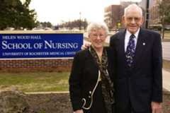Loretta Ford with her husband William J. Ford stands before the School of Nursing sign, commemorating Loretta Ford, who once served as dean.