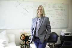 Political science professor Gretchen Helmke stands in her office with whiteboards and notes behind her.