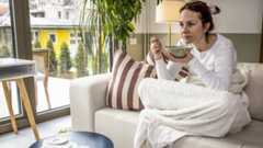 Woman on a sofa eating soup