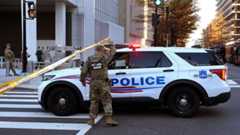 A member of the National Guard by a police car A member of the National Guard by a police car