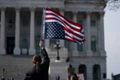 Woman holds an upside down US flag to protest against President Donald Trump outside the US Capitol ahead of his joint address to Congress in Washington, DC, on March 4, 2025. (ALLISON ROBBERT/AFP via Getty Images)