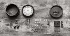 Parts of a wall clock lie on a table disassembled.