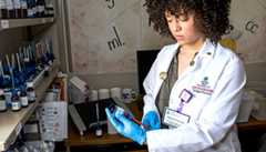 Pharmacy student in a lab filling a syringe from a vial. 
