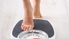 Two feet stepping onto a large black scale