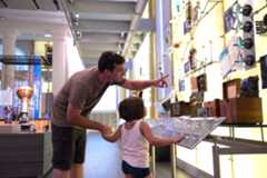 man pointing out a museum display to a child