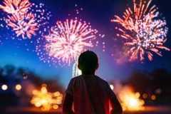 Vibrant fireworks display illuminating the night sky as a child watches with wonder. Celebrating with colorful explosions and bright lights.