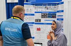 ISEF 2024 Los Angeles, CA - International Science and Engineering Fair - Display and Safety Volunteer talking with finalist about their project in the exhibit hall.