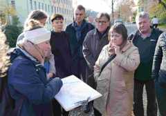 Menschen stehen im Halbkreis und schauen auf einen Stadtplan in ihrer Mitte.
