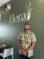 suman hoque standing in front of a sign with the name of his restaurant, Flora