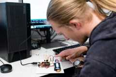 A student sits at a table using electronic equipment.