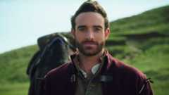 Joshua Sasse as Galavant standing in front of green hills with horse behind him in Galavant