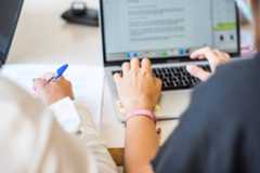 imagen de dos personas escribiendo y tomando notas en PC y folio