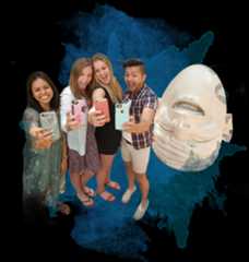 Four UCD students take a selfie next to one of our famous egghead statues.