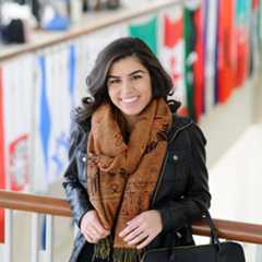 International student stands in front of flags on balcony in Campus Center.