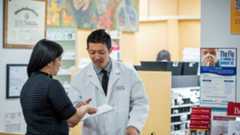 USC School of Pharmacy pharmacist helping a patient with paperwork