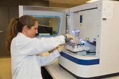 Woman in lab coat organizing microscope slides into storage container